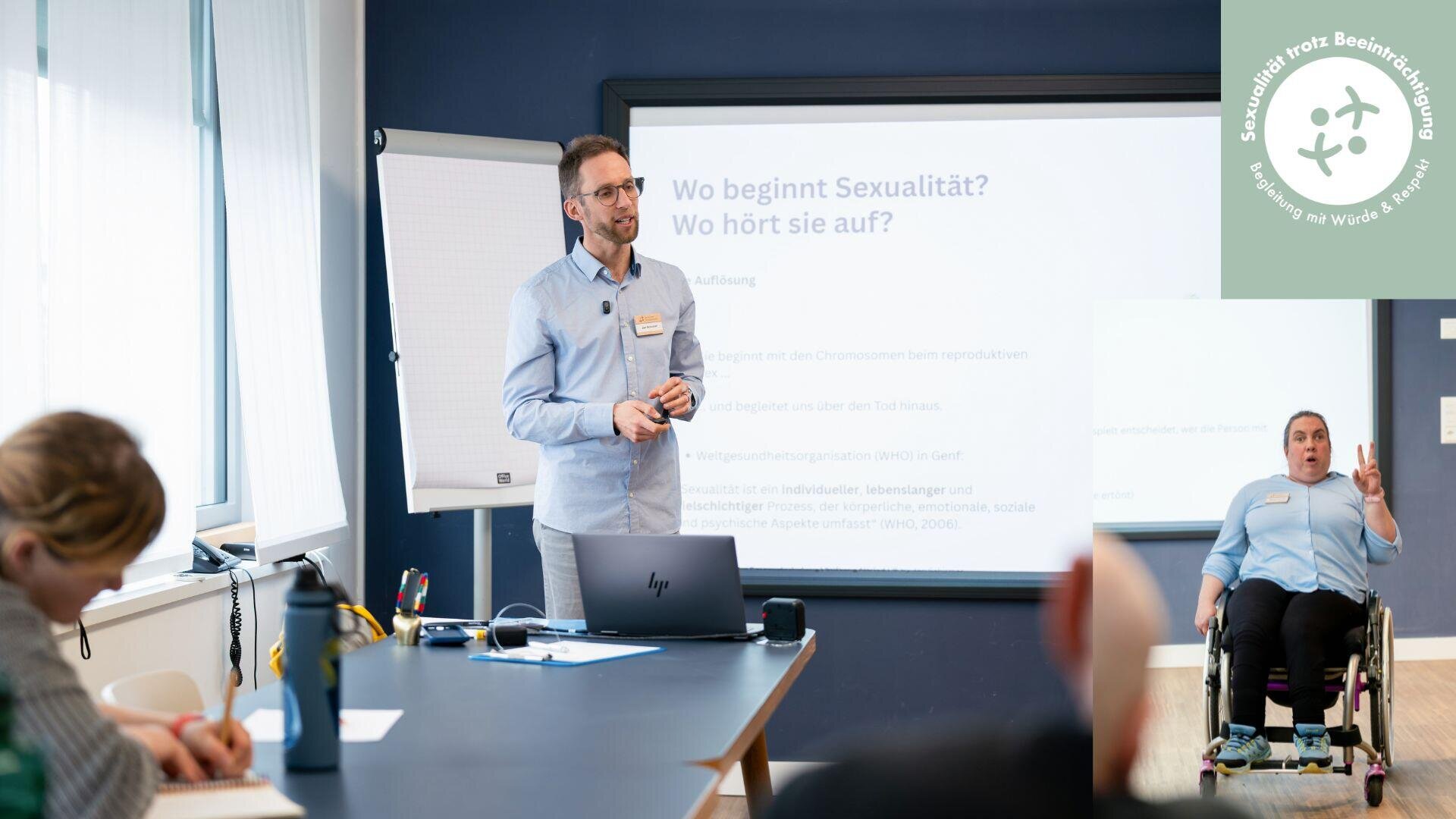 Ein Mann in einem hellblauen Hemd steht in einem Vortragsraum und spricht zu den Zuhörern, während hinter ihm auf einer Leinwand ein deutscher Text zum Thema Sexualität zu sehen ist.