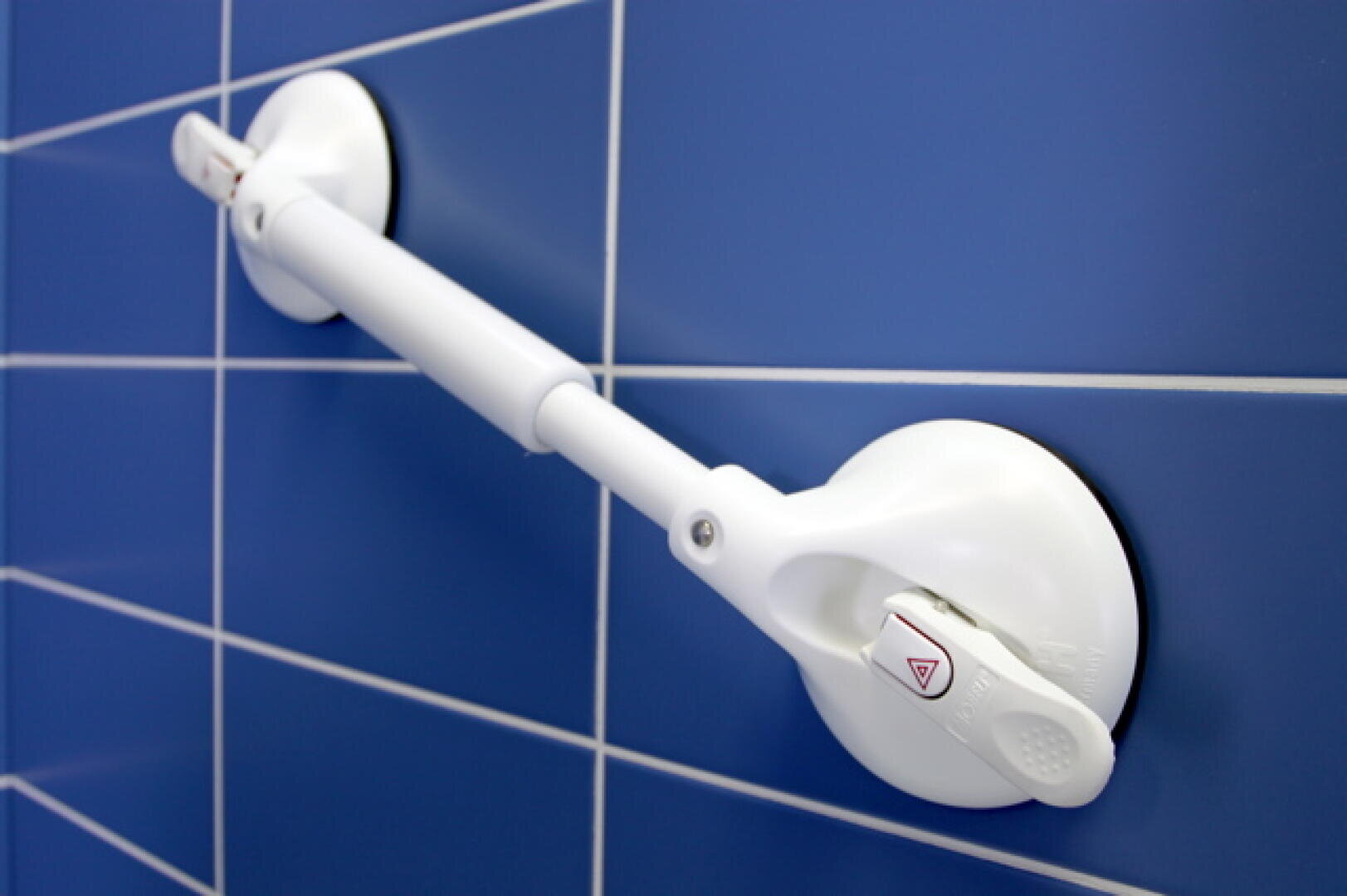 Ein weißer Sauggriff mit Verriegelungsmechanismen ist an einer blau gefliesten Wand befestigt und bietet Benutzern in Bereichen wie Badezimmern Halt und Stabilität.