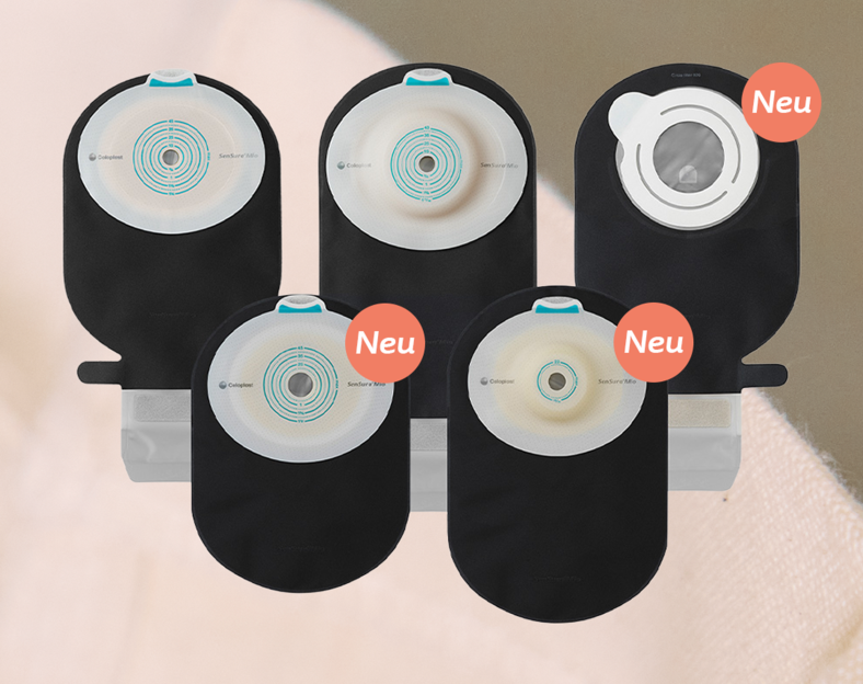 Fünf verschiedene schwarze und beige Stomabeutel sind aufrecht in zwei Reihen aufgestellt. Drei der Beutel sind mit orangefarbenen Neu-Plaketten gekennzeichnet, einer hat ein sichtbares Sichtfenster.